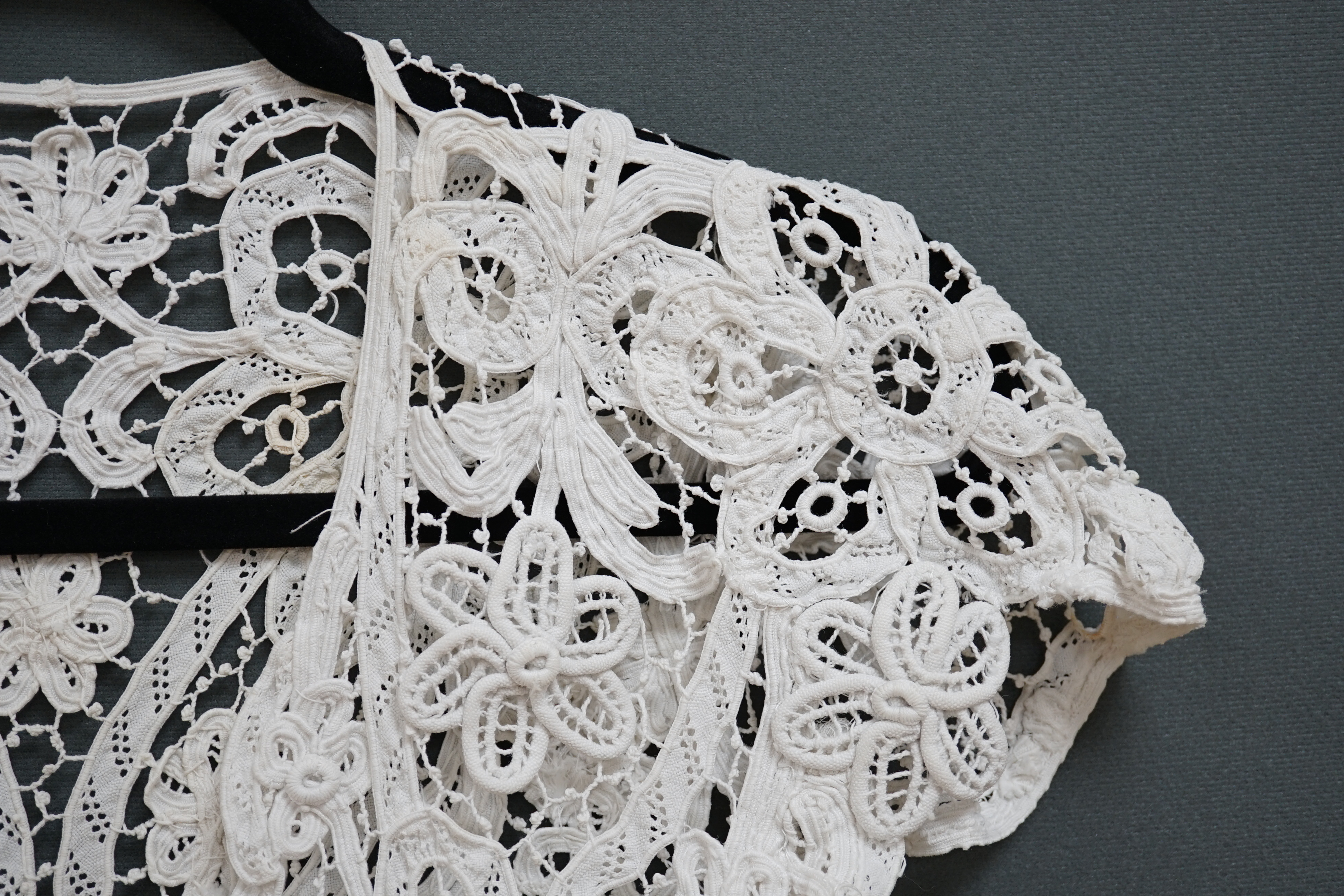 An Edwardian ladies white lace bolero, a tape lace Edwardian cap sleeve bolero with hand sewn bracts, attaching the tape lace together, possibly part of a wedding dress or summer dress, back under arm width 36cm. Conditi